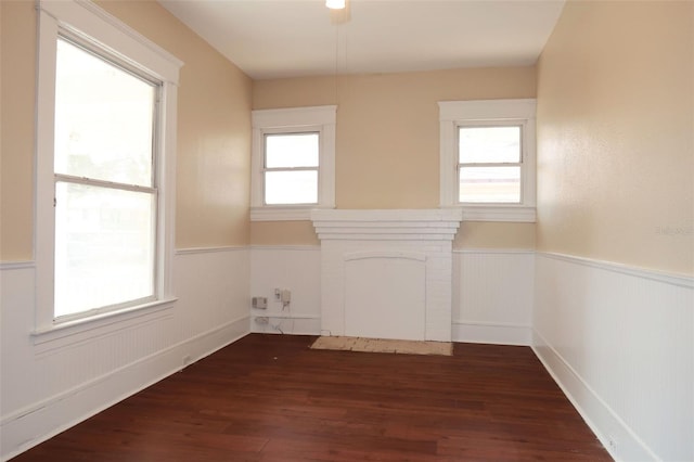 spare room with a wainscoted wall, a fireplace, and dark wood-style floors