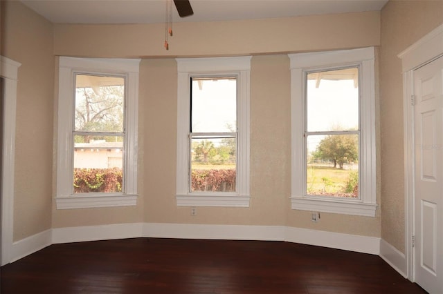 unfurnished room with dark wood-style floors, ceiling fan, and baseboards