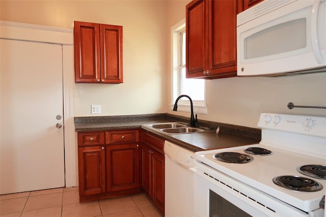 kitchen with dark countertops, white appliances, light tile patterned flooring, and a sink