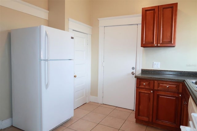 kitchen with dark countertops, light tile patterned floors, and freestanding refrigerator