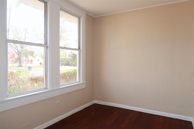 spare room featuring ornamental molding, dark wood-style flooring, and baseboards