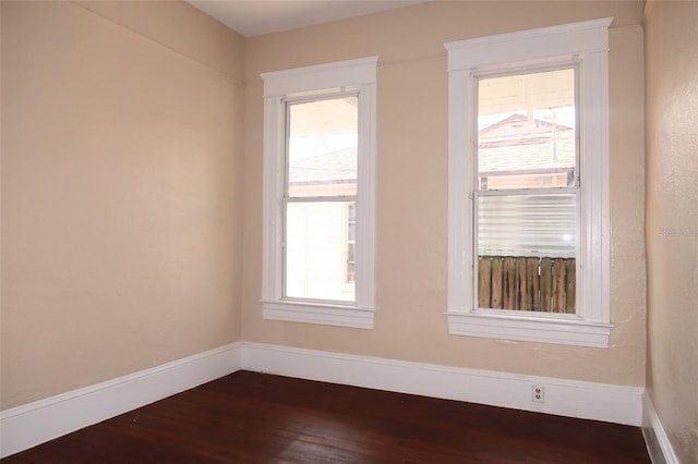 empty room featuring dark wood-type flooring and baseboards