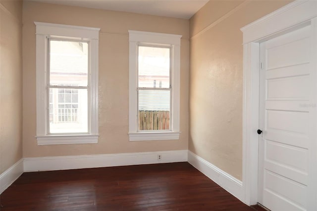 empty room featuring baseboards and dark wood-type flooring