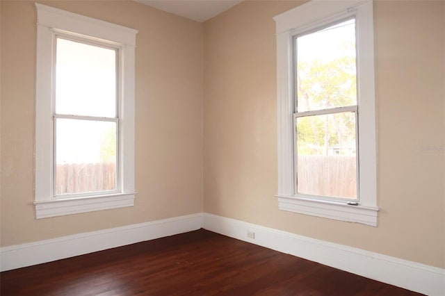 empty room with dark wood-style flooring and baseboards