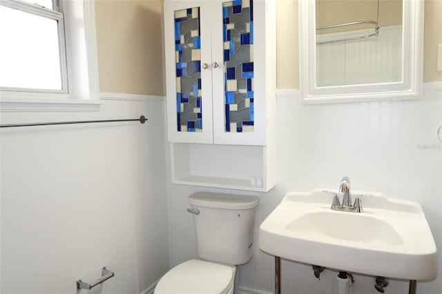 bathroom with toilet, a sink, and wainscoting