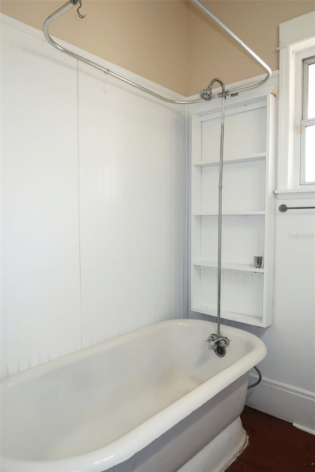 bathroom with a freestanding bath, wood finished floors, and baseboards