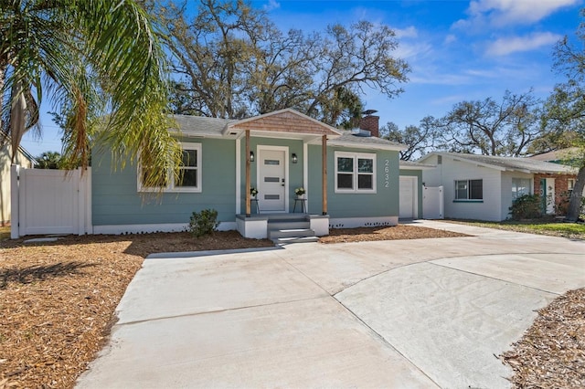 view of front of property with driveway, a garage, a chimney, a gate, and fence