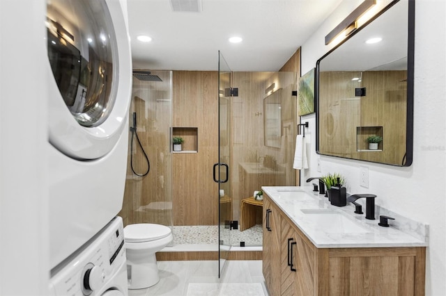 full bathroom with visible vents, stacked washer / dryer, toilet, a shower stall, and a sink