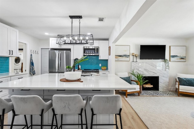 kitchen with stainless steel appliances, stacked washer / dryer, visible vents, white cabinets, and open floor plan