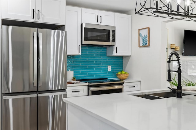 kitchen with light countertops, backsplash, appliances with stainless steel finishes, white cabinetry, and a sink