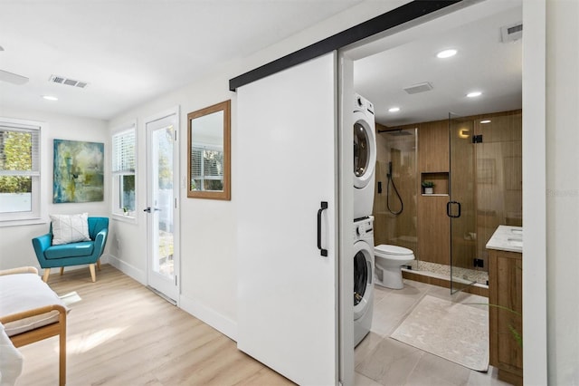 laundry room with recessed lighting, visible vents, stacked washer / dryer, laundry area, and baseboards