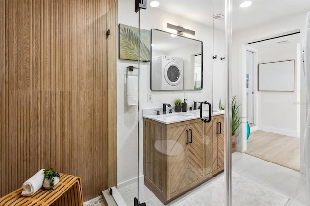 full bathroom featuring a walk in shower, double vanity, a sink, and baseboards