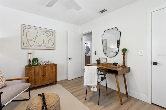 office space featuring light wood-style floors, visible vents, ceiling fan, and baseboards