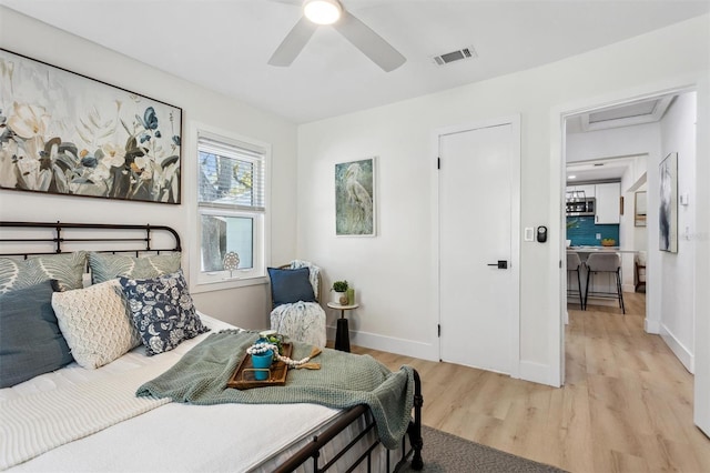 bedroom with a ceiling fan, baseboards, visible vents, light wood-style floors, and attic access