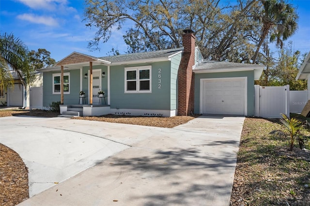 view of front facade with covered porch, an attached garage, a gate, fence, and driveway