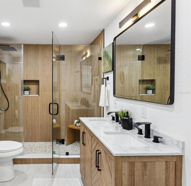 full bath featuring toilet, a stall shower, visible vents, and a sink