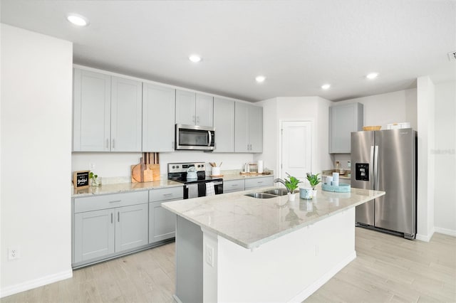 kitchen with stainless steel appliances, light wood-style floors, a sink, and gray cabinetry