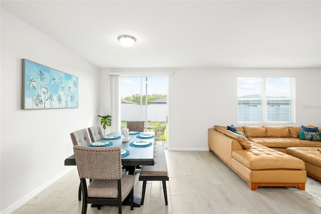 dining area with baseboards, plenty of natural light, and light wood finished floors