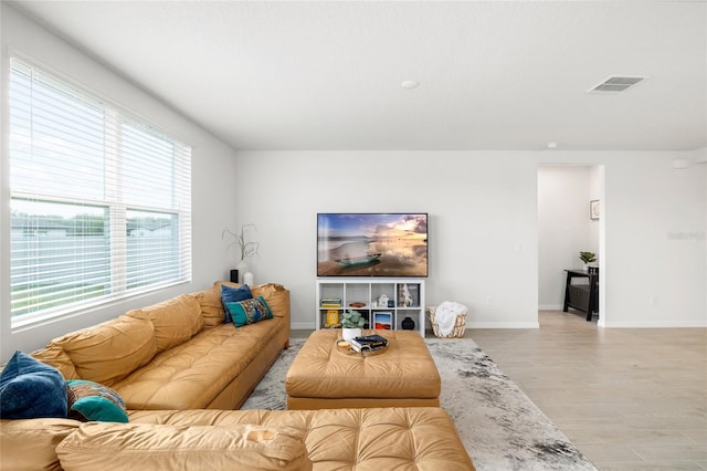 living area with light wood finished floors, visible vents, and baseboards