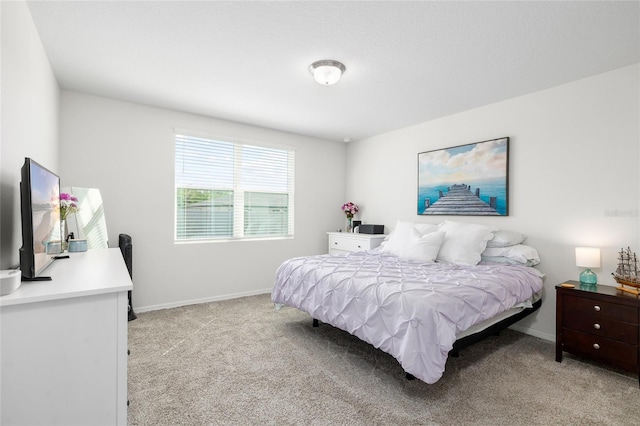 bedroom with light colored carpet and baseboards