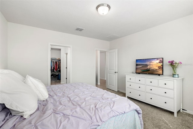 bedroom featuring visible vents, light carpet, baseboards, and a spacious closet