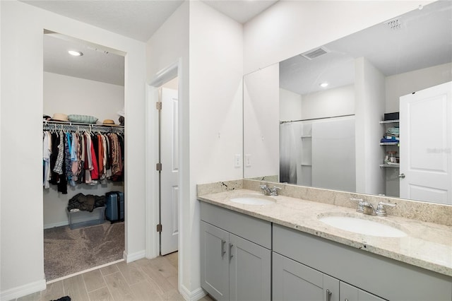 bathroom with wood finish floors, visible vents, a sink, and double vanity