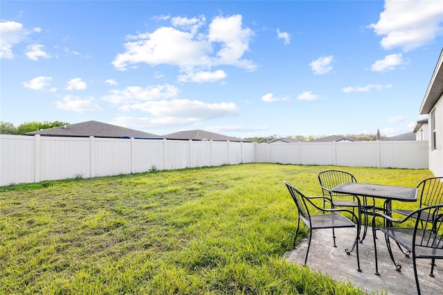 view of yard featuring fence and outdoor dining space