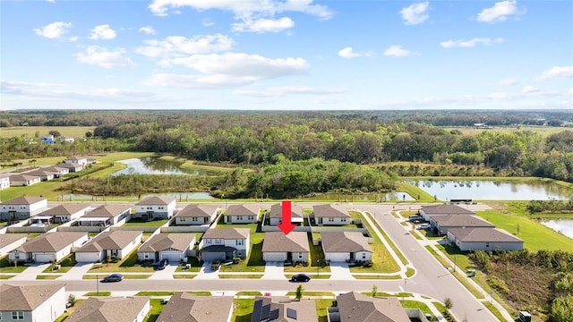 drone / aerial view featuring a forest view, a water view, and a residential view