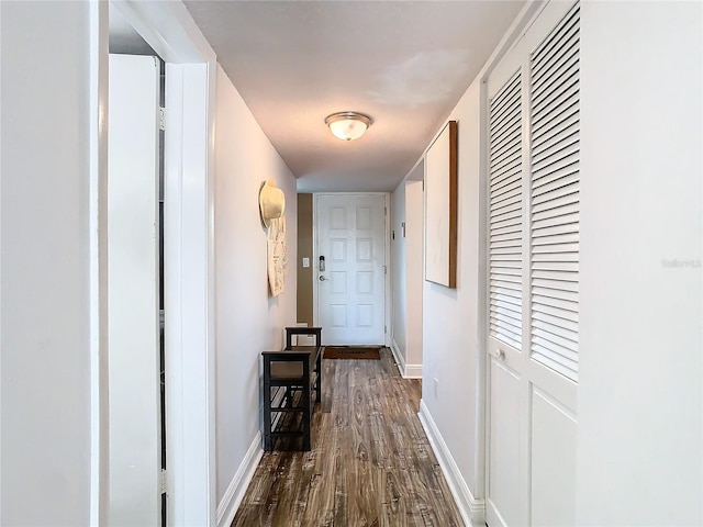 hallway with dark wood-type flooring and baseboards