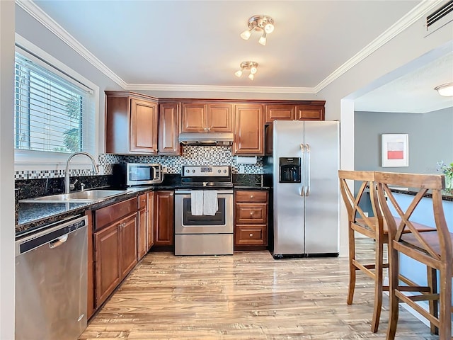 kitchen with under cabinet range hood, a sink, visible vents, appliances with stainless steel finishes, and light wood finished floors