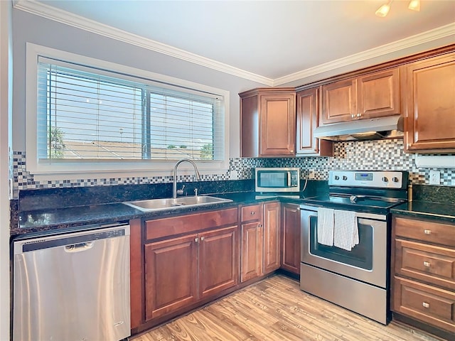 kitchen featuring appliances with stainless steel finishes, light wood-style floors, ornamental molding, a sink, and under cabinet range hood