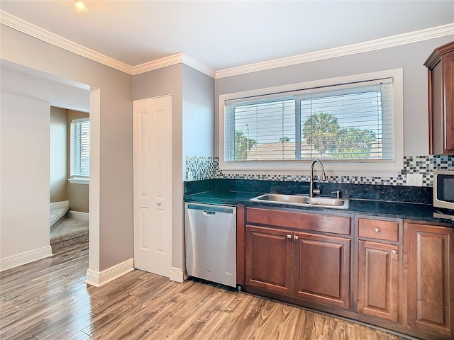 kitchen featuring stainless steel appliances, light wood-type flooring, dark countertops, and a sink