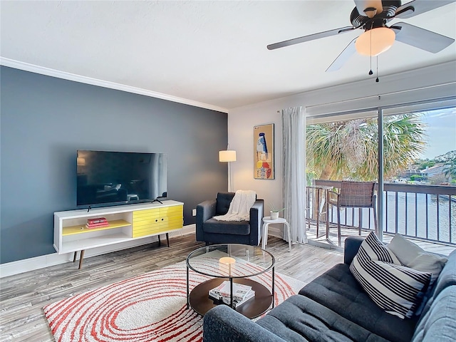 living room featuring ornamental molding, a ceiling fan, baseboards, and wood finished floors