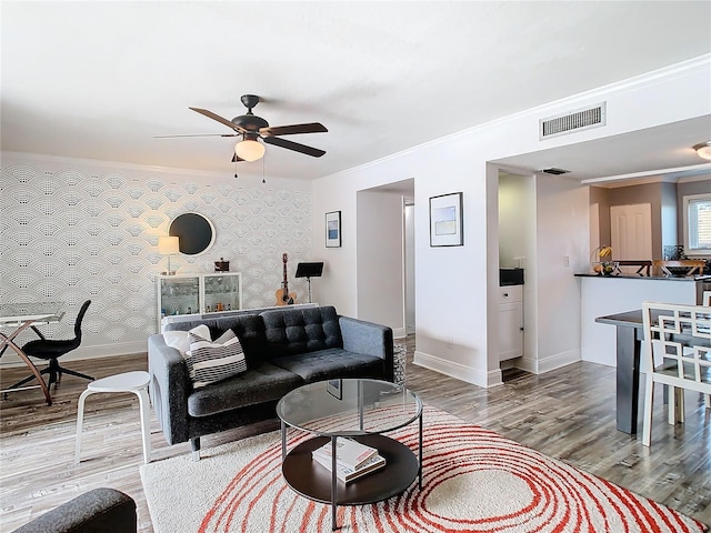 living room with baseboards, visible vents, wood finished floors, and ornamental molding