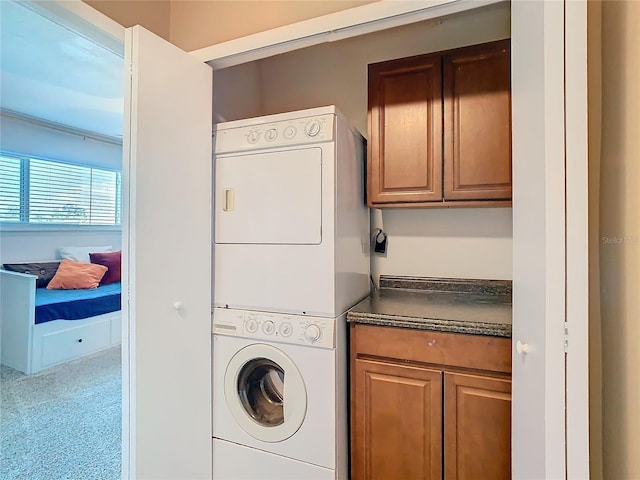 washroom with stacked washer and clothes dryer and cabinet space