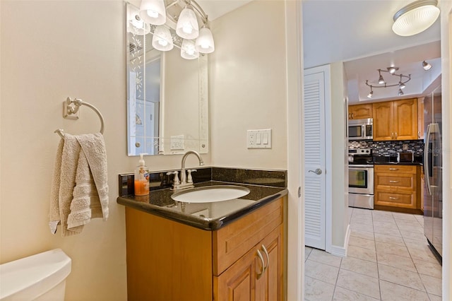 half bathroom with tasteful backsplash, vanity, toilet, and tile patterned floors