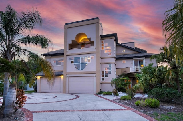 view of front of home with driveway, a balcony, an attached garage, and stucco siding