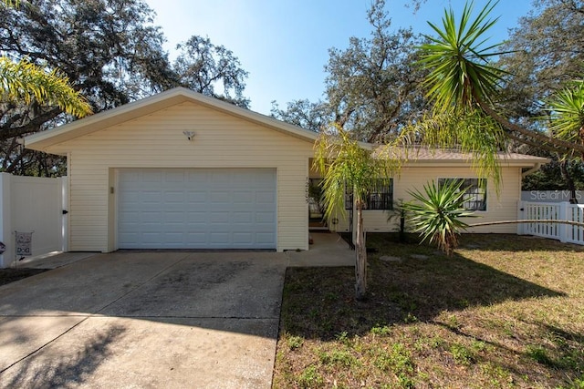 view of front of house featuring concrete driveway, an attached garage, and fence