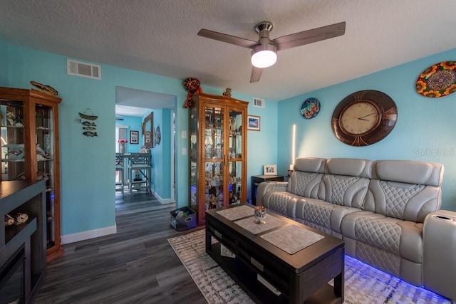 living area with visible vents, ceiling fan, a textured ceiling, and wood finished floors