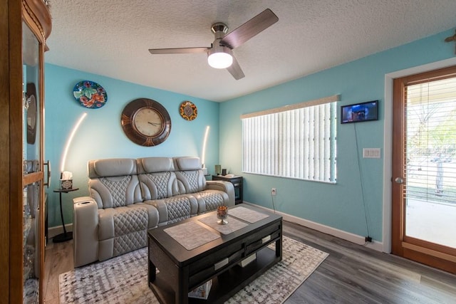 living area featuring ceiling fan, a textured ceiling, baseboards, and wood finished floors