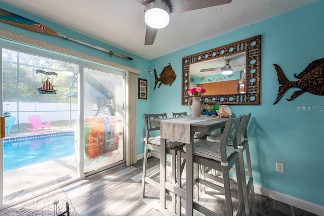 dining space featuring ceiling fan, baseboards, a textured ceiling, and wood finished floors