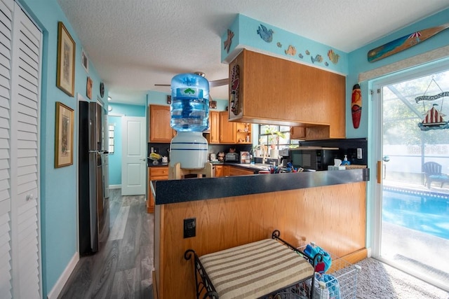 kitchen featuring dark countertops, visible vents, a textured ceiling, a peninsula, and black appliances