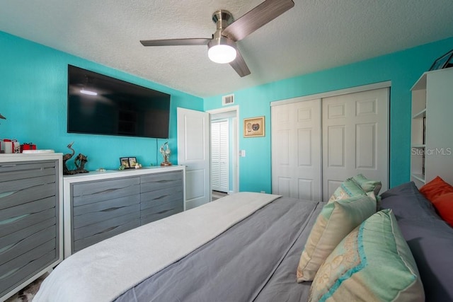 bedroom with a closet, visible vents, ceiling fan, and a textured ceiling