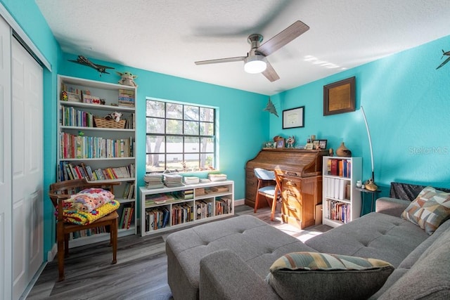 sitting room featuring ceiling fan, a textured ceiling, and wood finished floors