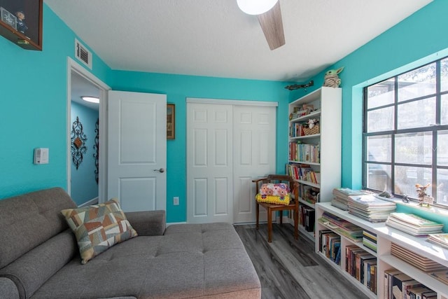 living area with visible vents, ceiling fan, and wood finished floors