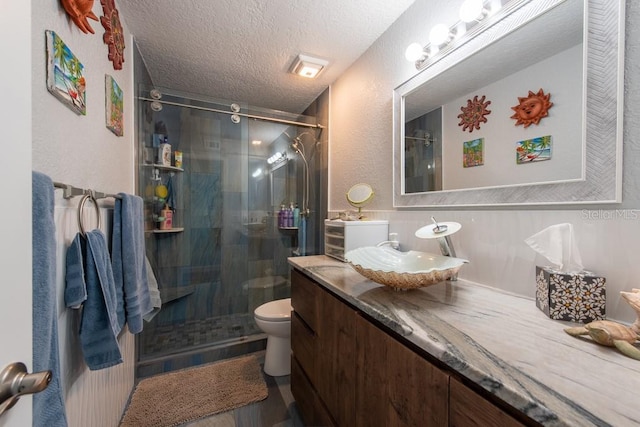 full bathroom with toilet, a stall shower, a textured ceiling, and vanity