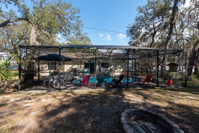 exterior space featuring glass enclosure, an outdoor fire pit, an outdoor pool, and a patio