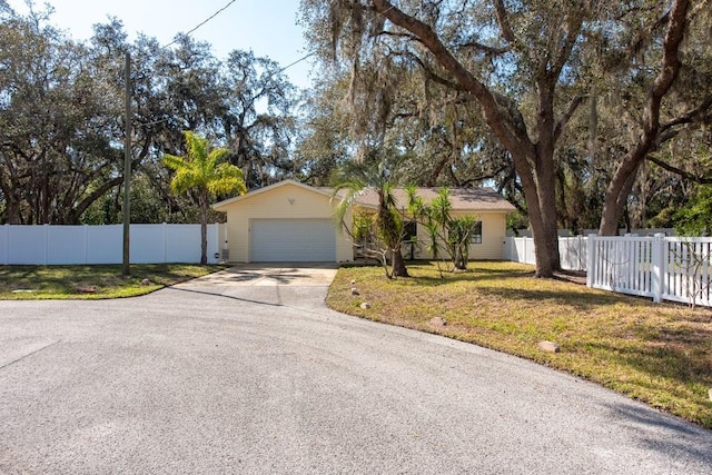 single story home featuring driveway, an attached garage, fence, and a front yard