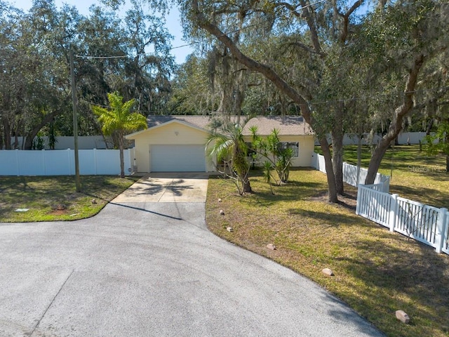 ranch-style house with a garage, concrete driveway, fence, and a front lawn