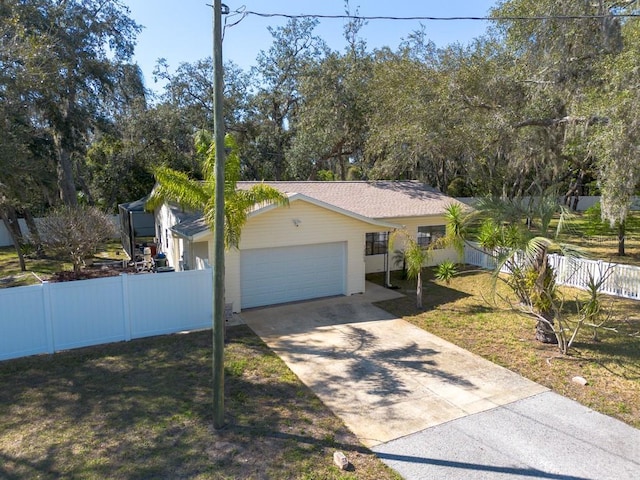 single story home featuring a front yard, concrete driveway, fence, and an attached garage